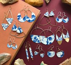 several pairs of blue and white earrings are on a red surface next to some rocks