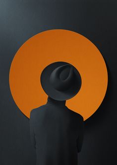 a person with a hat on standing in front of an orange and black circular background