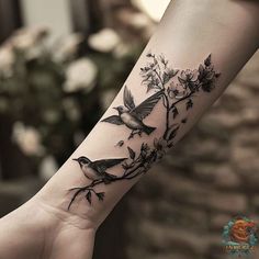 a bird on a branch with flowers and leaves is shown on the wrist tattoo design