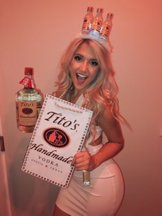 a woman wearing a tiara holding up a sign with vodka bottles on top of her head