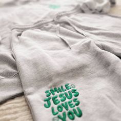 Smile Jesus Loves You Set. Introducing our first set! The Smile Jesus Loves You set :) Share your faith with the most comfy set. Including emerald green embroidery featured on the leg of the shorts and the left chest. The pieces of the set can be purchased separately (Crew only or shorts only) OR together. See info on each piece below Sweatshirt Info: * 50% cotton, 50% polyester * Pre-shrunk * Classic fit * 1x1 athletic rib knit collar with spandex * Air-jet spun yarn with a soft feel and reduce Christian Merch Aesthetic, Christian Drip, Scripture Clothing, Jesus Apparel, Jesus Clothing, Christian Crewneck, Letter Designs