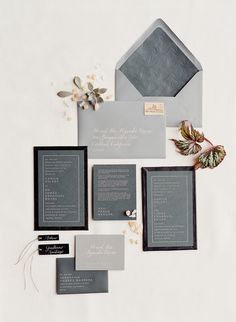 the wedding stationery is laid out in shades of gray and black, along with matching envelopes