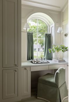 a green chair sitting in front of a window next to a desk with a laptop on it