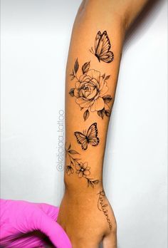 a woman's arm with butterflies and roses tattoo on her left arm, next to a pink glove