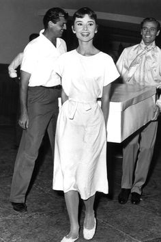 a woman standing next to two men in front of a table with a box on it