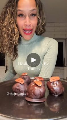 a woman standing in front of some chocolates on top of a metal tray with nuts