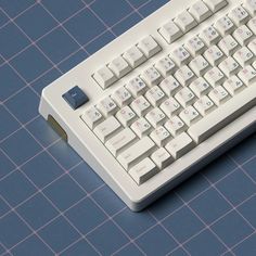 a white computer keyboard sitting on top of a blue tiled floor next to a mouse