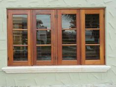 two windows with wooden frames on the side of a building