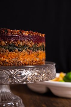 a cake sitting on top of a metal platter next to a plate of food