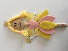 a wooden doll head on top of a yellow and pink hair comb with stars around it