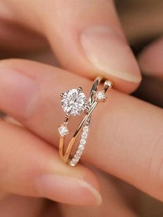 a woman's hand holding an engagement ring with two diamonds on the top and bottom