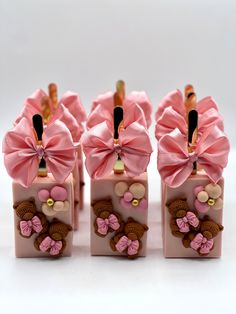 four pink candy boxes with bows and teddy bears on them are sitting side by side