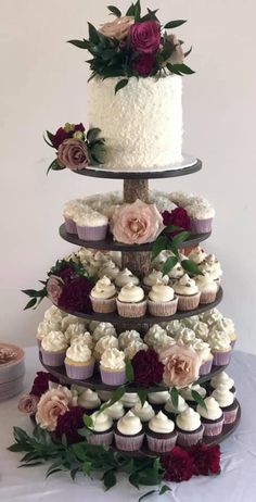 a three tiered cake with cupcakes and flowers on it