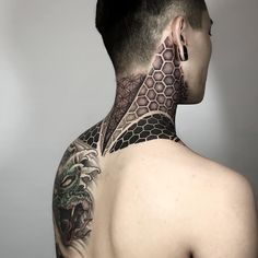 the back of a man's head with tattoos on his neck and shoulder, in front of a gray background