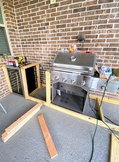 an outdoor bbq grill is being built in front of a brick wall and door