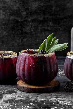 three glasses filled with red liquid and topped with green leafy garnishes