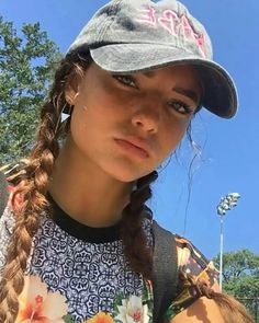 a girl with braids wearing a hat and looking at the camera