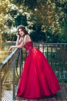 a woman in a red dress leaning on a railing