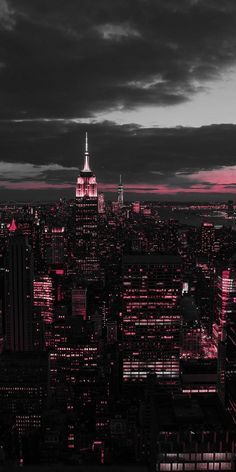 the city skyline is lit up in pink and white at night, as seen from above