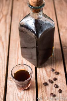 a bottle of coffee sitting on top of a wooden table next to a glass cup