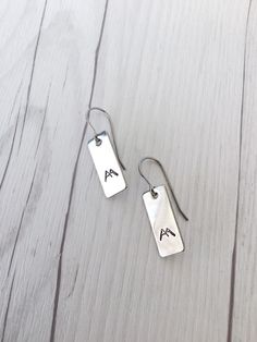 "Looking for beautiful but durable jewelry? Look no further than stainless steel! These mountain earrings are hand stamped stainless steel, with stainless steel ear wires. They won't irritate your skin like other metals can, and they won't discolor or tarnish either. Light and comfortable, these earrings won't get in your way, and will always look great. -All stainless steel -Hand stamped -3/4\" stainless steel rectangle -Gift wrapping included Customer satisfaction is my highest priority. Pleas Everyday Rectangular Stainless Steel Jewelry, Everyday Stainless Steel Rectangular Jewelry, Everyday Dangle Earrings In Stainless Steel, Minimalist Surgical Steel Earrings As Gift, Everyday Silver Surgical Steel Earrings, Everyday Rectangular Nickel Free Earrings, Everyday Hand Stamped Stainless Steel Jewelry, Everyday Rectangular Nickel-free Earrings, Everyday Nickel-free Rectangular Earrings