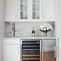 a kitchen with white cabinets and stainless steel appliances, including a wine cooler in the center