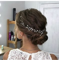 a woman with her hair up in a bun wearing a bridal tiara and pearls