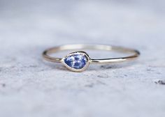 a gold ring with a blue stone in the center on top of a cement surface