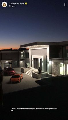 an image of a house at night with cars parked in the driveway and lights on