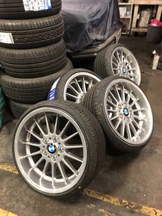 four bmw rims and tires stacked on top of each other in a garage area