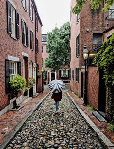 a person walking down a cobblestone street with an umbrella in their hand,