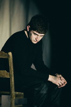 a young man sitting on top of a wooden chair