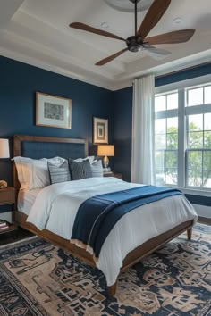 a bedroom with blue walls and white bedding, carpeted flooring and ceiling fan