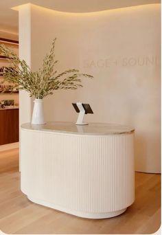 a vase with some flowers sitting on top of a counter in front of a wall