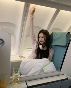 a woman sitting on an airplane with her arms up