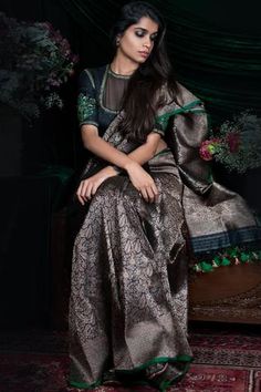 a woman sitting on top of a wooden bench wearing a dress and holding a flower in her hand