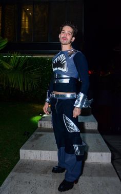 a young man dressed in costume standing on steps at night with his hands in his pockets