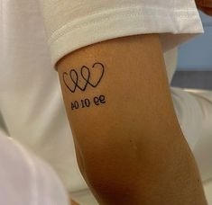 a person with a tattoo on their arm that reads 10 00 and has two hearts in the middle