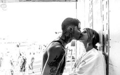 a man and woman kissing each other in front of a wall