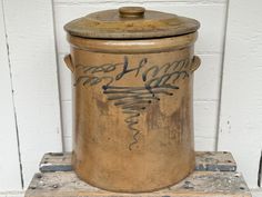 an old metal container with writing on it sitting on a pallet in front of a white brick wall