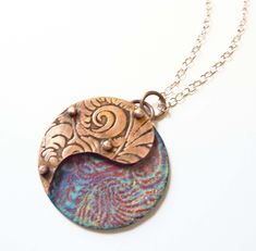 Yin Yang Enamel Necklace, Riveted Paisley, Copper Pendant, Artisan Jewelry, Mixed Media, 3D Layered, Hand Enameled Jewelry, Boho Necklace The top layer of this pendant is embossed with a geometric design and hand-sawed in a paisley shape from copper sheet, and then oxidized to highlight the pattern. The top layer is then riveted atop tiny tubes over a hand-enameled abstract floral pattern on a copper base plate in shades of blue, red, and yellow. The stacked and riveted layers create a 3-D effec Artistic Multicolor Copper Jewelry, Artistic Copper Jewelry With Soldered Details, Artistic Copper Jewelry, Bronze Jewelry With Artistic Design, Artistic Bronze Jewelry With Artistic Design, Artisan Copper Necklaces With Engraved Details, Artisan Engraved Copper Necklaces, Unique Artistic Copper Jewelry, Spiritual Patina Copper Necklace