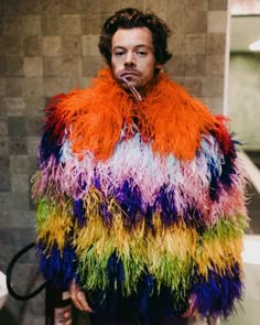 a man in a multicolored jacket standing next to a toilet