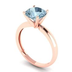 a rose gold engagement ring with a blue topazte stone in the center, on a white background