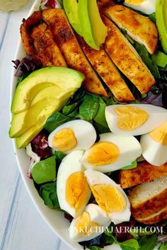 a salad with hard boiled eggs, avocado and spinach on the side