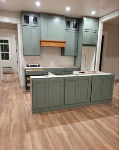 an empty kitchen with wooden floors and green cabinets in the center, is being remodeled