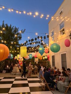 people are sitting at tables in front of colorful lights and paper lanterns hanging from the ceiling