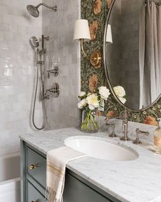 a white sink sitting under a bathroom mirror next to a bathtub and shower head