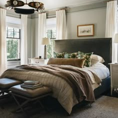 a bedroom with a large bed and two windows