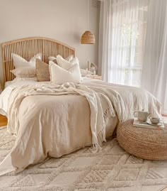 a bed with white linens and pillows in a bedroom next to a large window