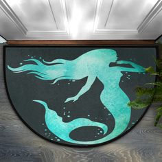 a door mat with a mermaid silhouette painted on the front and side of it next to a potted plant